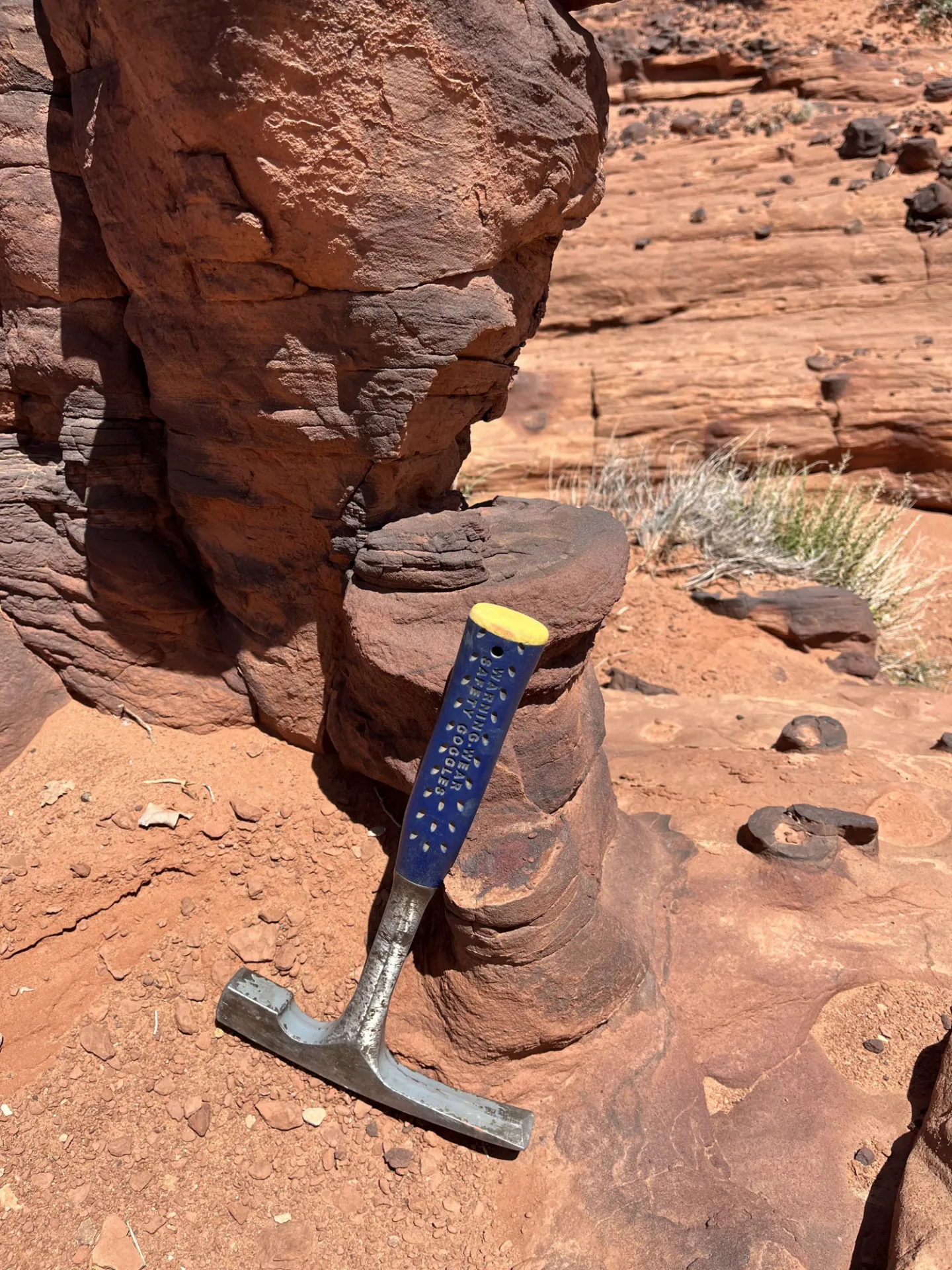 geologic hammer resting on an iron oxide pipe